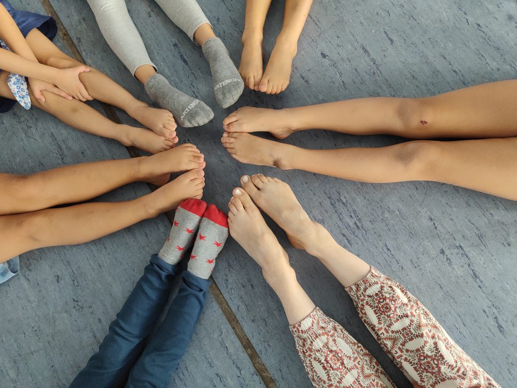 Pointed legs of children sitting in a circle with dance teacher